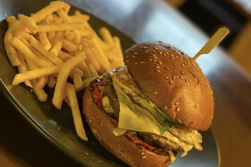 Casa Mia Burger mit Spiegelei und Pommes auf dunklem Teller