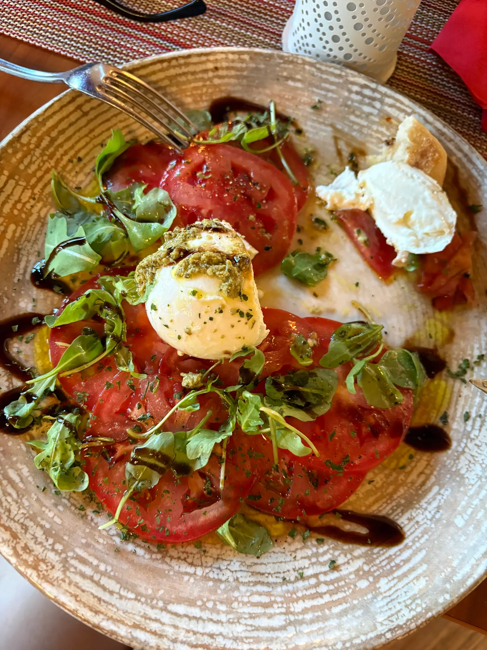 Tomaten mit Mozzarella, Rucola und Balsamico auf einem hellen Teller