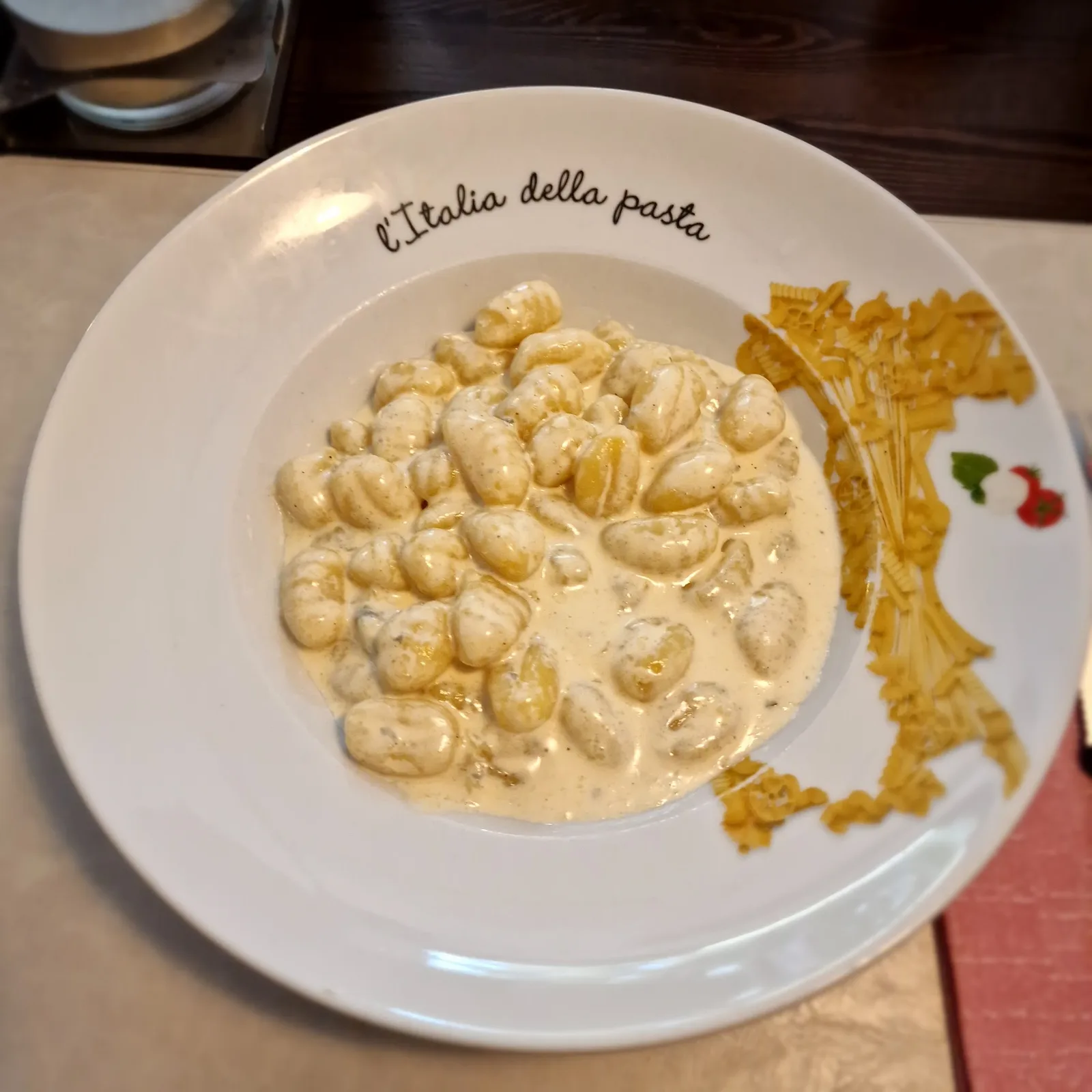 Gnocchi in Gorgonzolasauce auf einem Teller mit dem Umriss Italiens